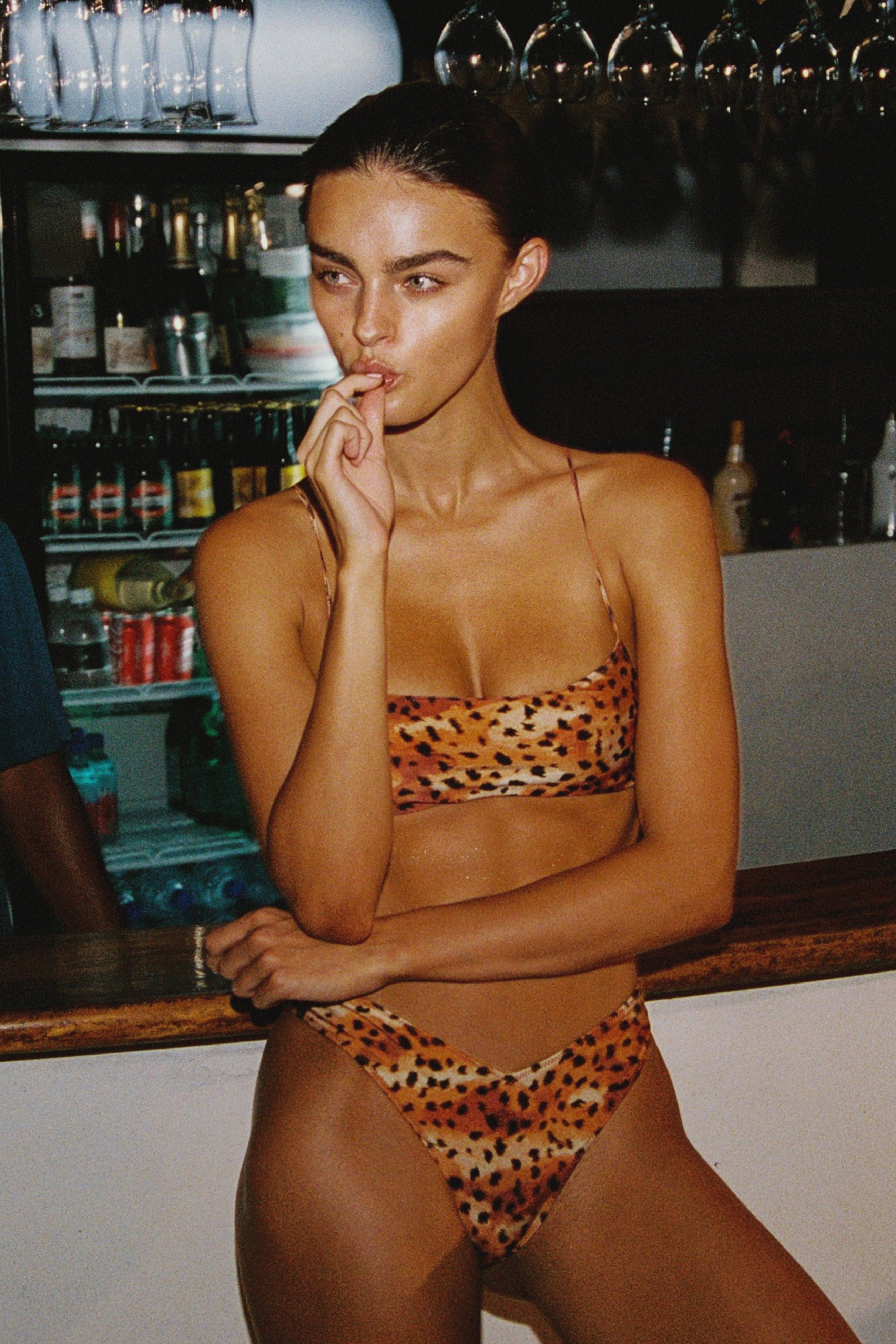 Model wearing a leopard print bikini in a bar setting