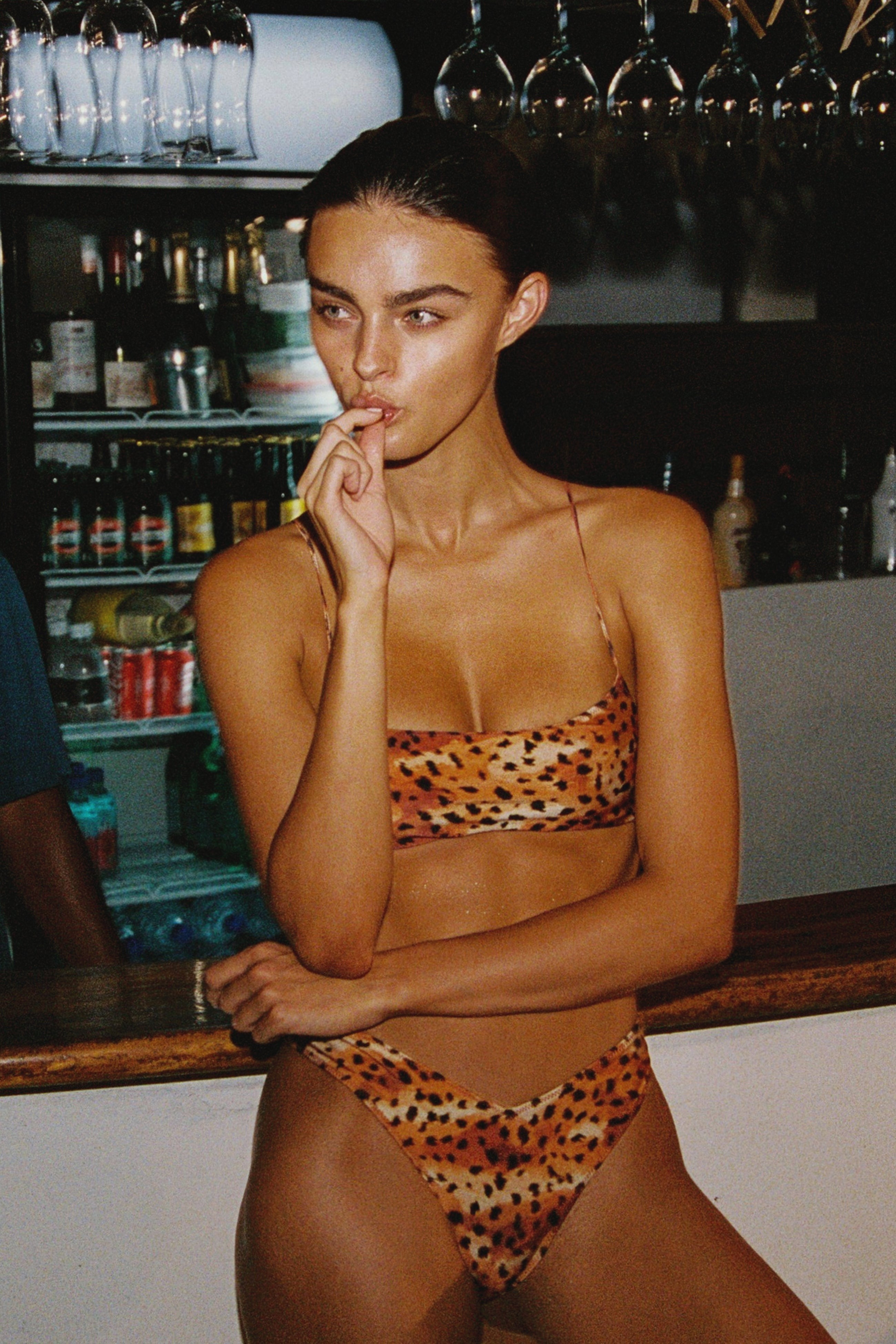 Model wearing a leopard print bikini in a bar setting