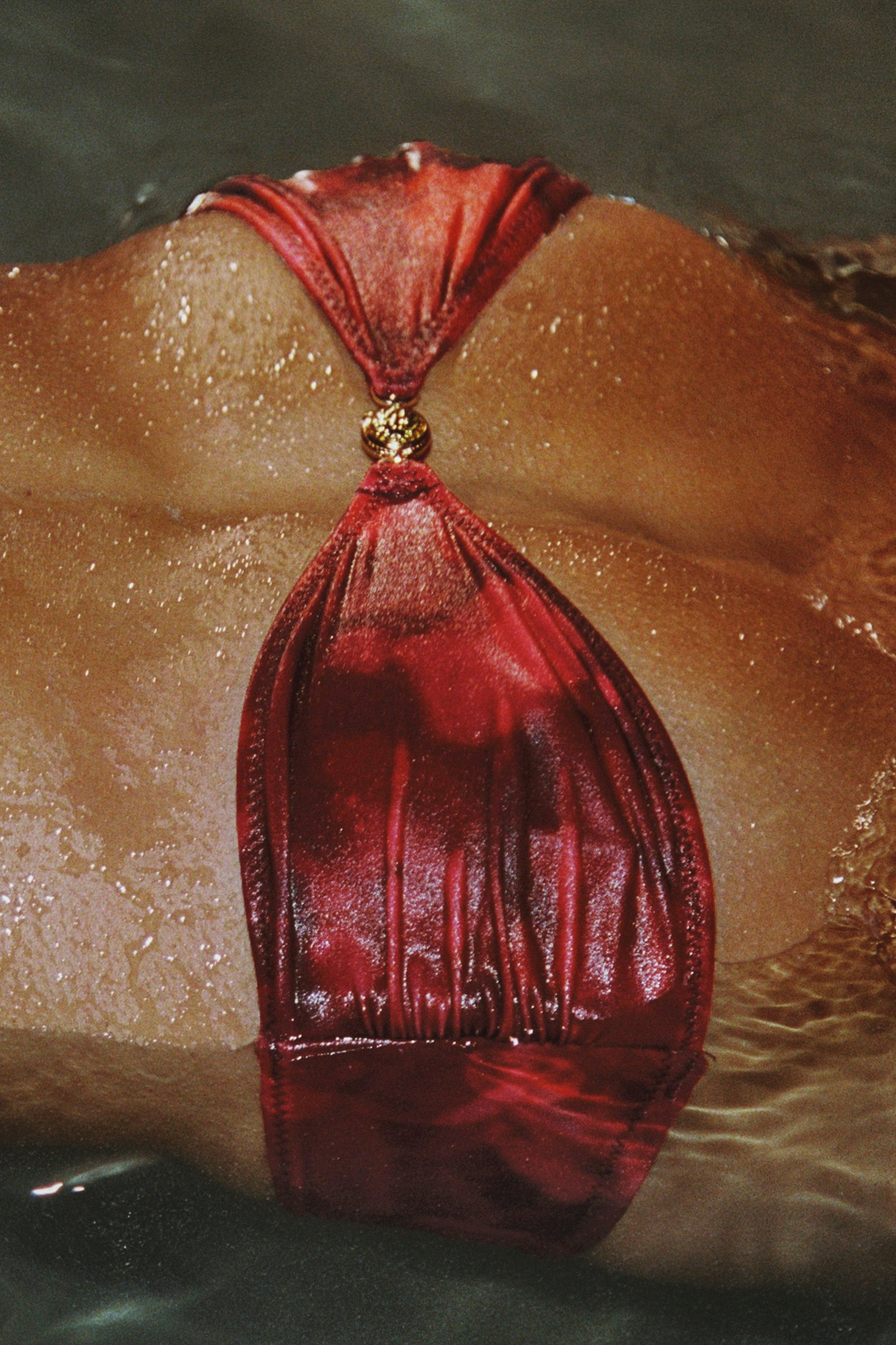 Red leather bag with a gold clasp on a textured surface