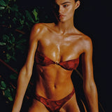 Woman in a red bikini sitting outdoors with greenery in the background