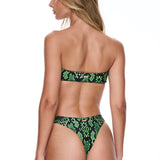 Woman wearing a green and black patterned bikini on a white background